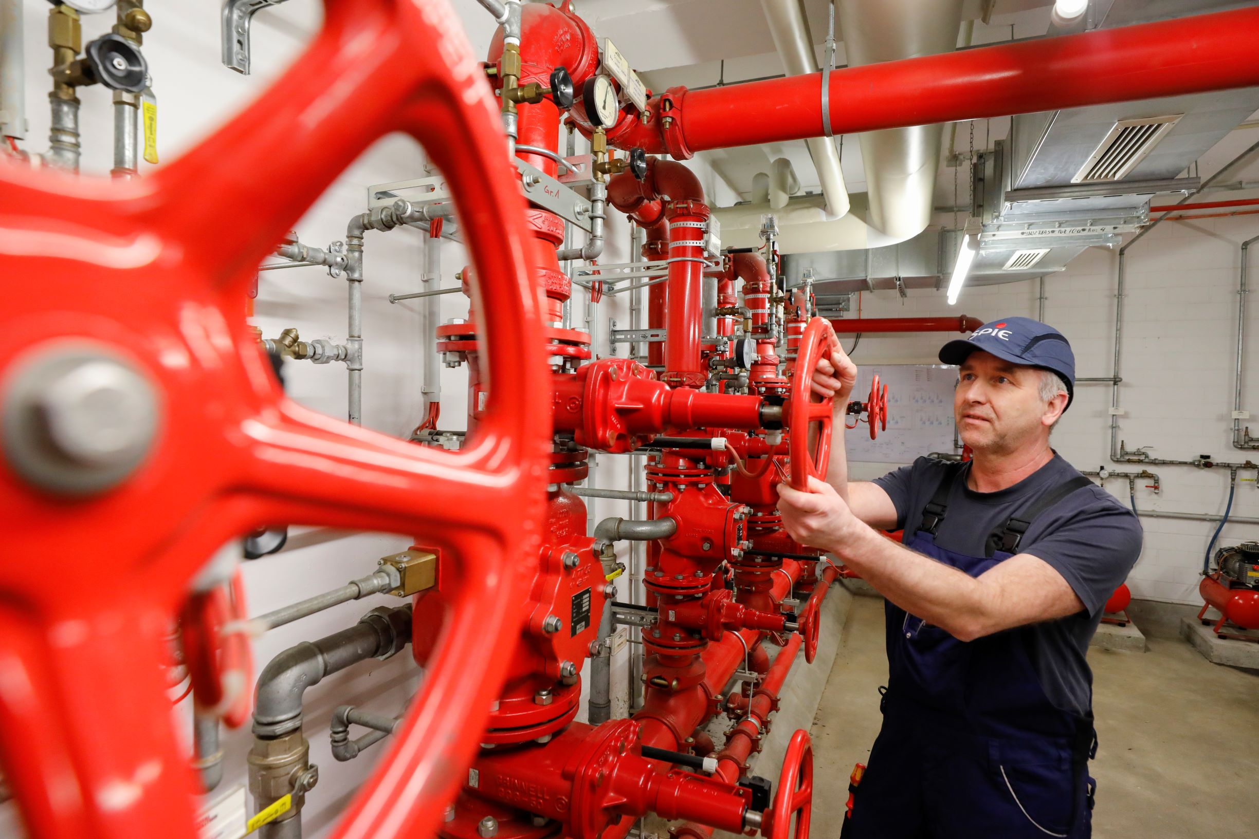SPIE Techniker männlich in Arbeitskleidung dreht an einem Ventil einer Leitungsanlage - Bildnachweis: SPIE