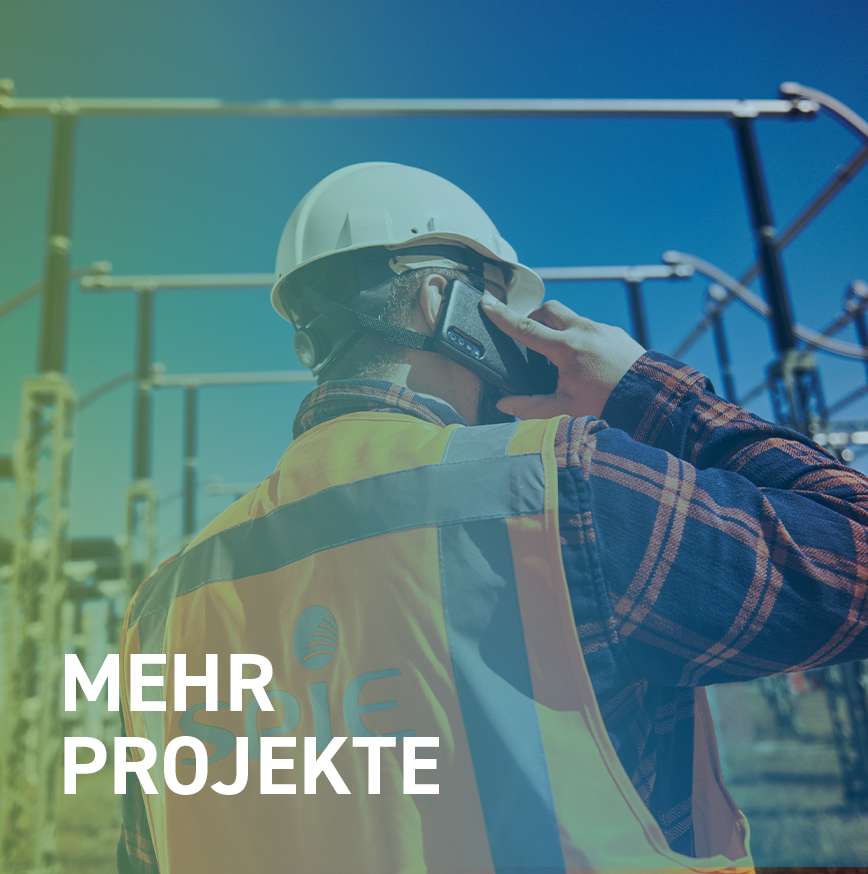 Person mit SPIE Sicherheitsjacke telefoniert mit seinem Smartphone auf der Umspannwerk-Baustelle